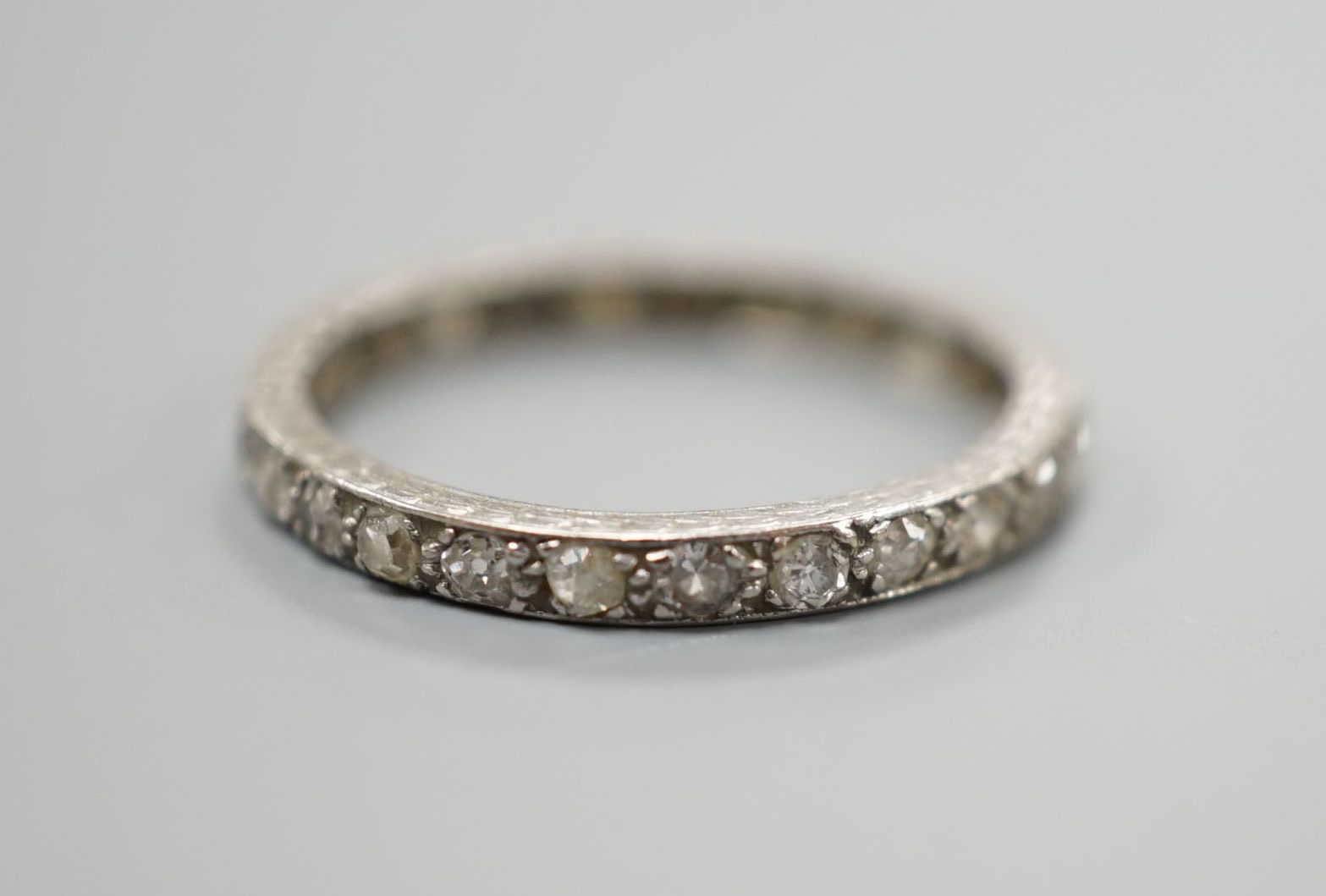 A white metal and diamond chip set full eternity ring, size M, gross weight 2.1 grams.